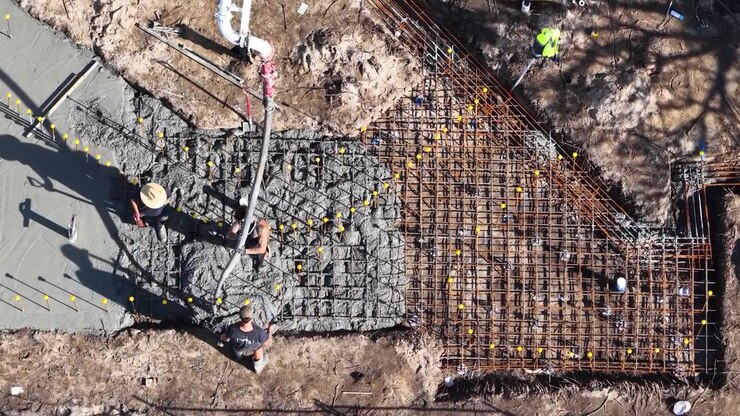 Drohnenaufnahme von oben: Bauarbeiter gießen nassen Beton über Bewehrungsstahl in Broadbeach Waters, Australien