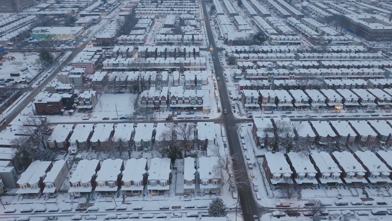 Aerial drone footage panning across historic row homes in snow covered neighborhoods in West Philadelphia, Pennsylvania.