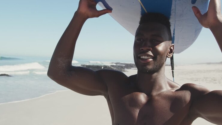 African American man holding a surfboard on his head