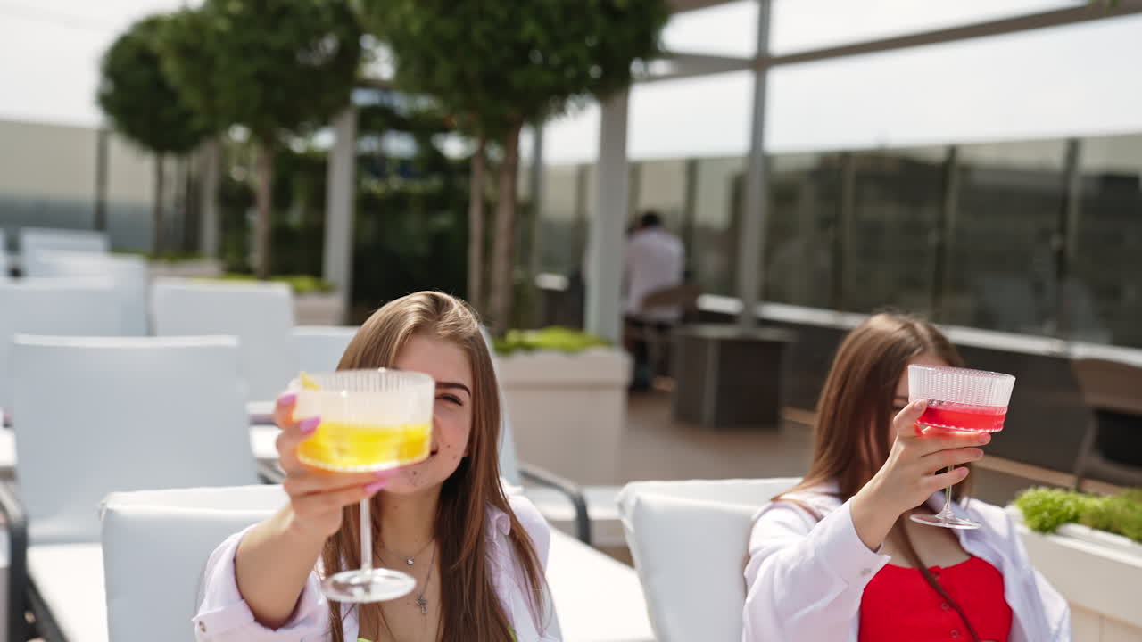Cheerful happy relaxing girls raise their glasses with cocktails. Ladies enjoying life and vacation time. Blurred backdrop.
