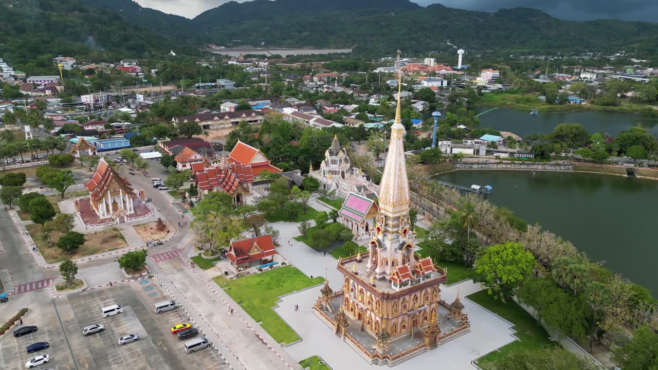 Video trên không về quần thể chùa Wat Chalong ở Phuket, Thái Lan, được bao quanh bởi cây xanh tươi tốt, cảnh quan thành phố và những ngọn đồi phía xa