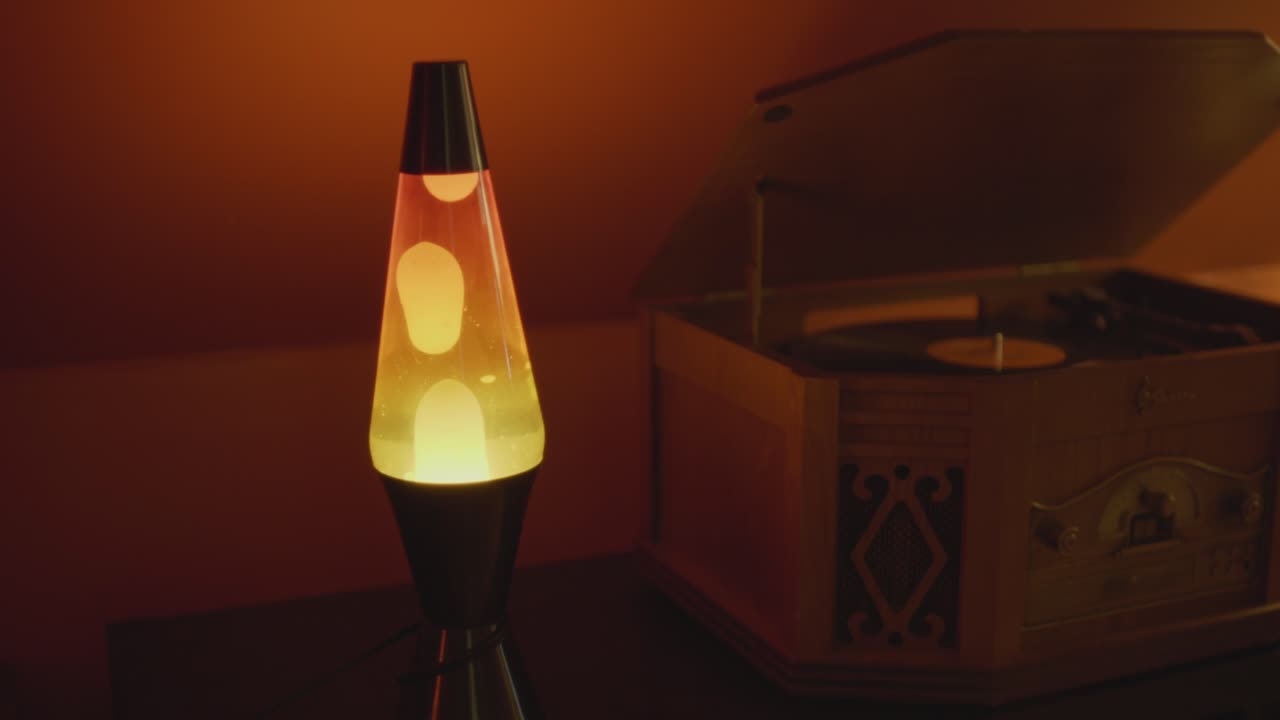 A lava lamp and record player in a warm and vintage setting. Orange lighting and bubbles create a retro 70s atmosphere. Shot in 60 Frames for slow motion
