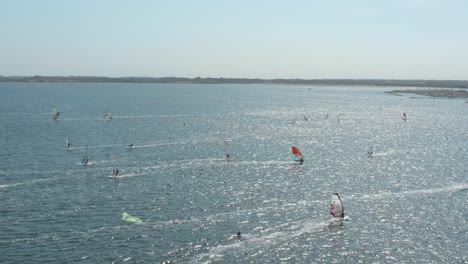 Drone---Aerial-shot-of-many-surfers-on-a-blue,-wavy-and-windy-sea-on-a-sunny-day-with-white-clouds-on-a-island,-Zeeland,-Netherlands,-30p