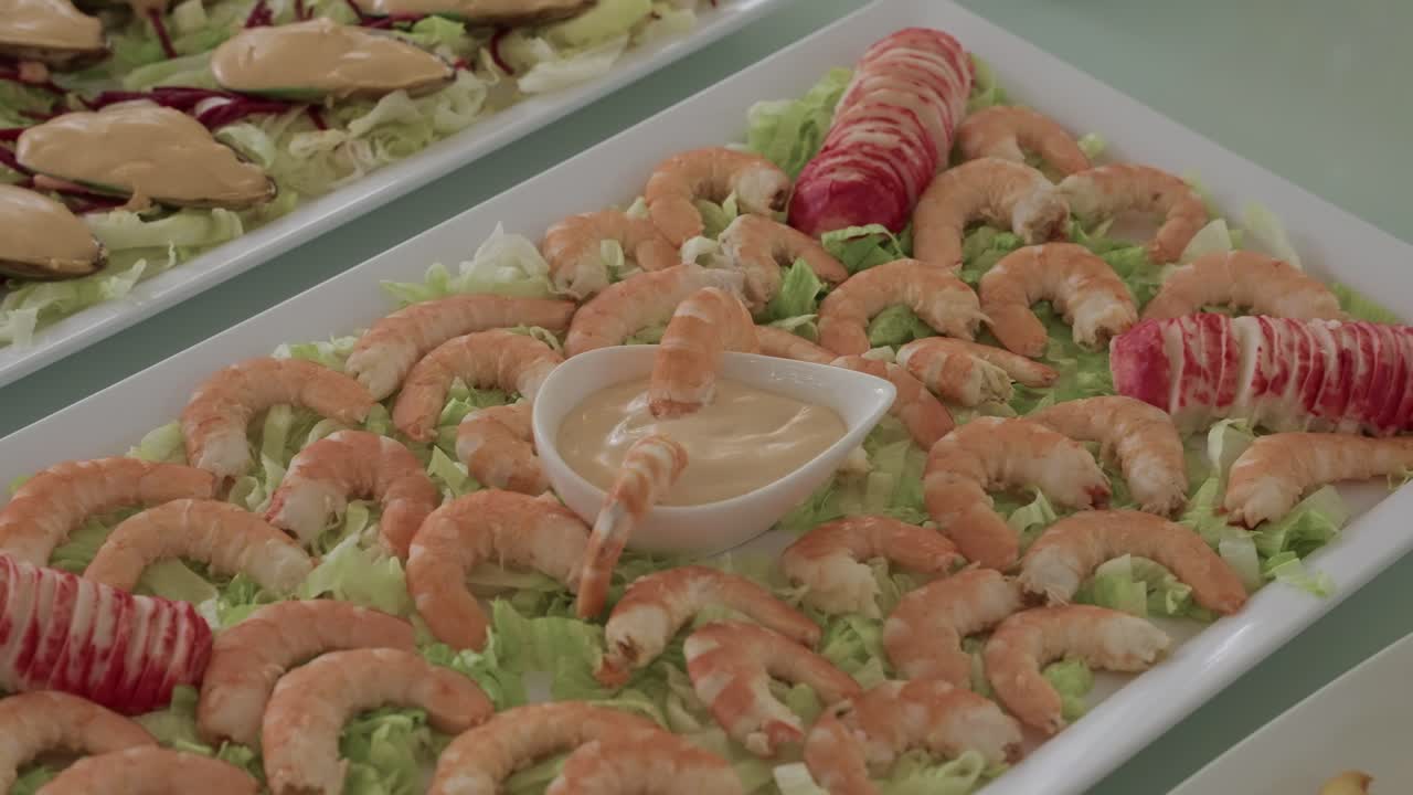 Gambas cocidas dispuestas con salsa y palitos de cangrejo sobre lechuga