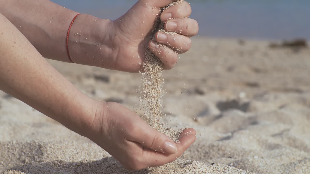Sand falling from hand in slow motion on a beach. Vacation and travel concept. Shot on super slow motion camera 1000 fps.