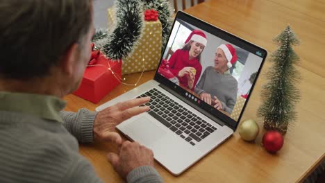 Happy-caucasian-senior-man-on-video-call-with-senior-friends-at-christmas-time