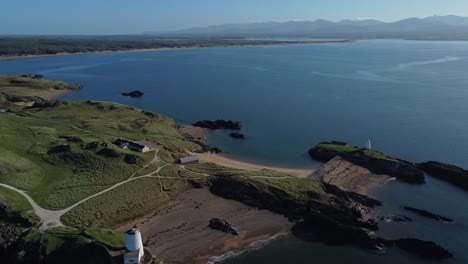 vista aérea del faro de ynys llanddwyn con la nebulosa cordillera de snowdonia a través del brillante mar de irlanda al amanecer