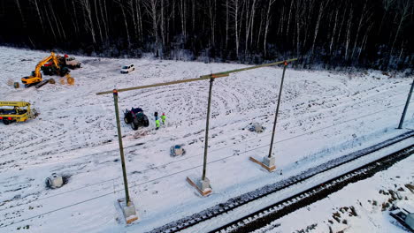 Aerial-view-of-worker-repairing-overhead-wire-on-railroad-during-snowy-day