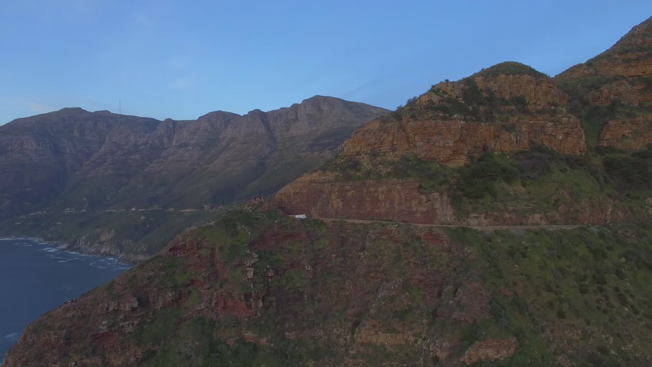 Scogliere e montagne di Chapmans Peak Drive sulla costa oceanica dall'alto, vista aerea durante il tramonto nella Penisola del Capo in Sudafrica