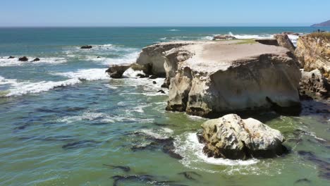 a rocky and rugged shoreline with waves gently rolling in from the pacific ocean in slow motion