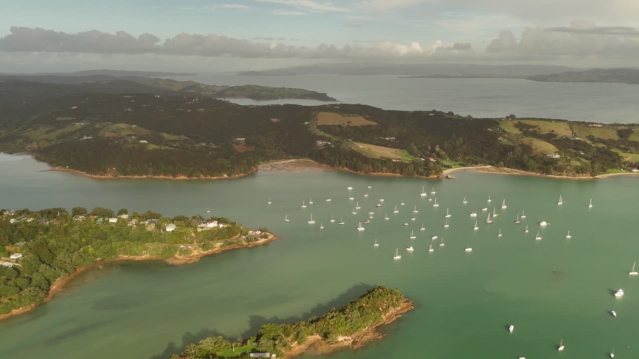 Sunset time with anchored boats and yachts on water of Surfdale area with Shelly Beach and luxury villas. Aerial Panorama view. Haiheke Island, New Zealand.