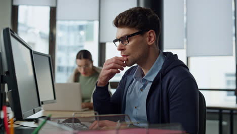 thoughtful programmer looking computer at desk. focused it man analysing code