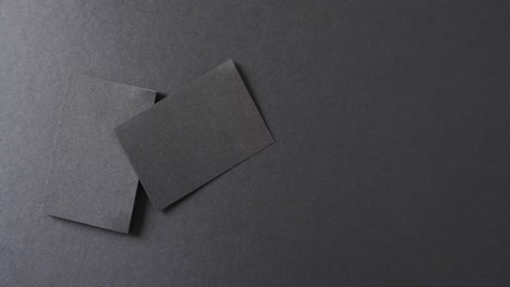 overhead view of blank black business cards on black background, copy space, slow motion