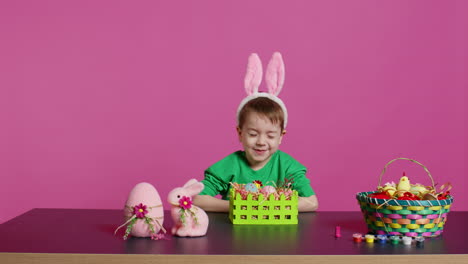 excited little kid decorating baskets with eggs and grass to prepare for easter