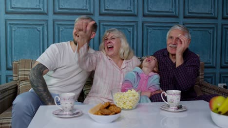 multigenerational happy family laughing, watching cartoons television movies, showing thumbs down