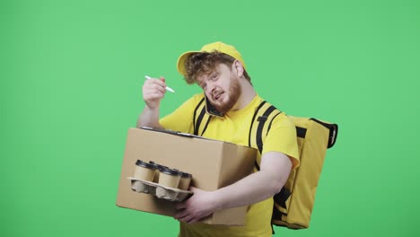 retrato de hombres jóvenes llenando documentos de entrega, hablando por teléfono. hombre pelirrojo en uniforme de mensajero de entrega amarillo con bolsa térmica posando en pantalla verde. primer plano. cámara lenta lista 59.97fps