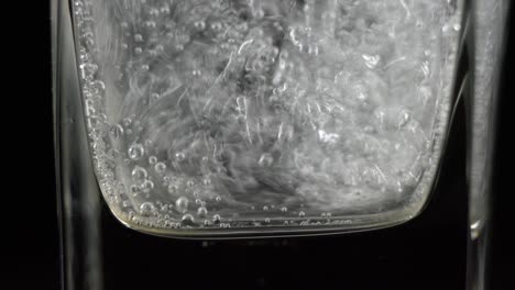 close up of mineral water bubbles in the glass. macro shop of carbonated fresh sparkling drink with oxygen balls on dark background