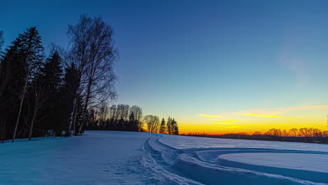 Idílico-Paisaje-De-Nieve-Con-Puesta-De-Sol-Dorada-En-El-Fondo-En-Una-Fría-Noche-De-Invierno---Toma-De-Lapso-De-Tiempo---Colores-Cambiantes-En-El-Cielo