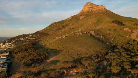 Coche-Conduciendo-Hacia-La-Vía-De-La-Tubería-Y-La-Cabeza-De-Los-Leones-En-Segundo-Plano-Al-Atardecer-En-Ciudad-Del-Cabo,-Antena