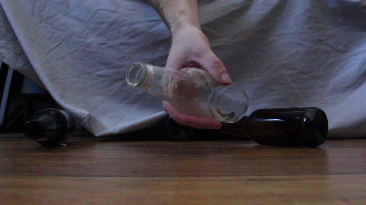 자고 있는 취한 남자에게서 맥주병이 떨어지고 굴러간다