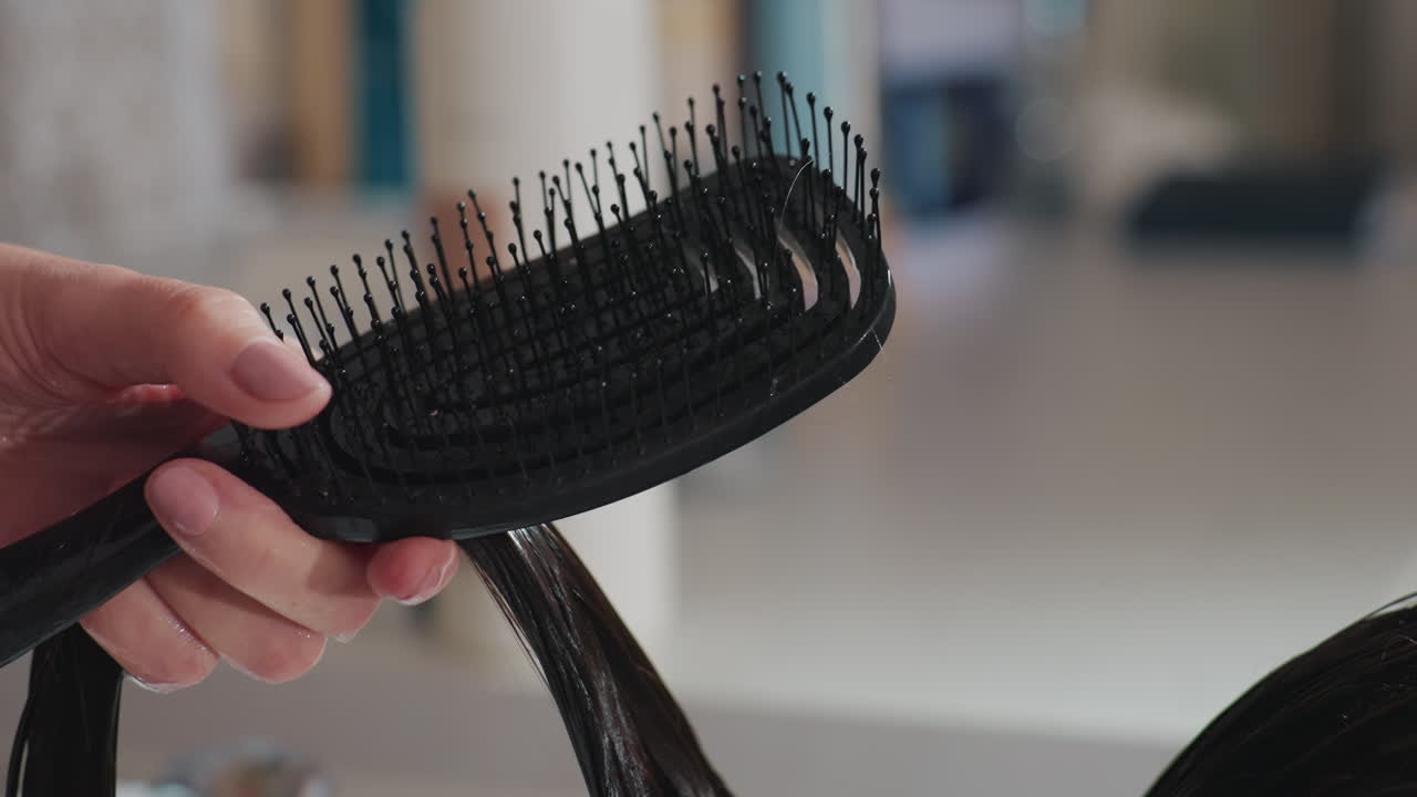 Técnica de cepillado y alisado del cabello cuidadosa, peinado centrado con movimientos precisos del cepillo sobre mechones de cabello húmedo, desenredado preciso y alisado del cabello húmedo con cepillo de pala y separaciones.