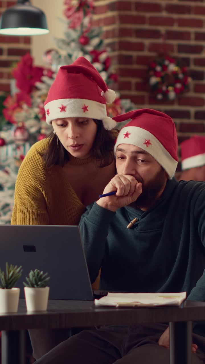 Couple wearing Santa hats using laptop during Christmas