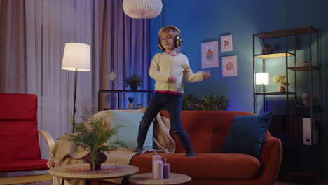 una niña feliz con auriculares bailando un baile de moda mientras escucha música en casa sola