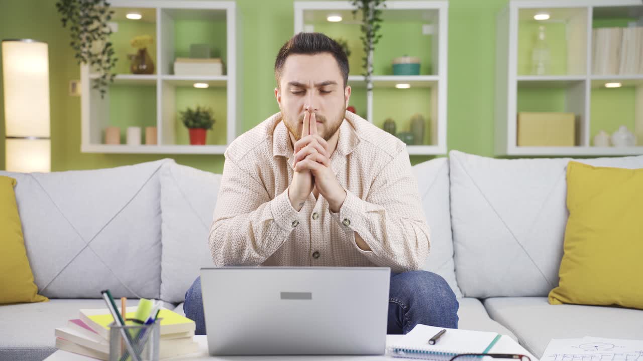 Giovane uomo nervoso pensa a cosa fare al computer e si stressa.