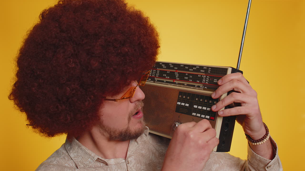 Glad hipster mand bruger retro vintage båndoptager til at lytte til musik, diskodanser og har det sjovt
