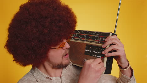 happy hipster man using retro vintage tape record player to listen music, disco dancing having fun