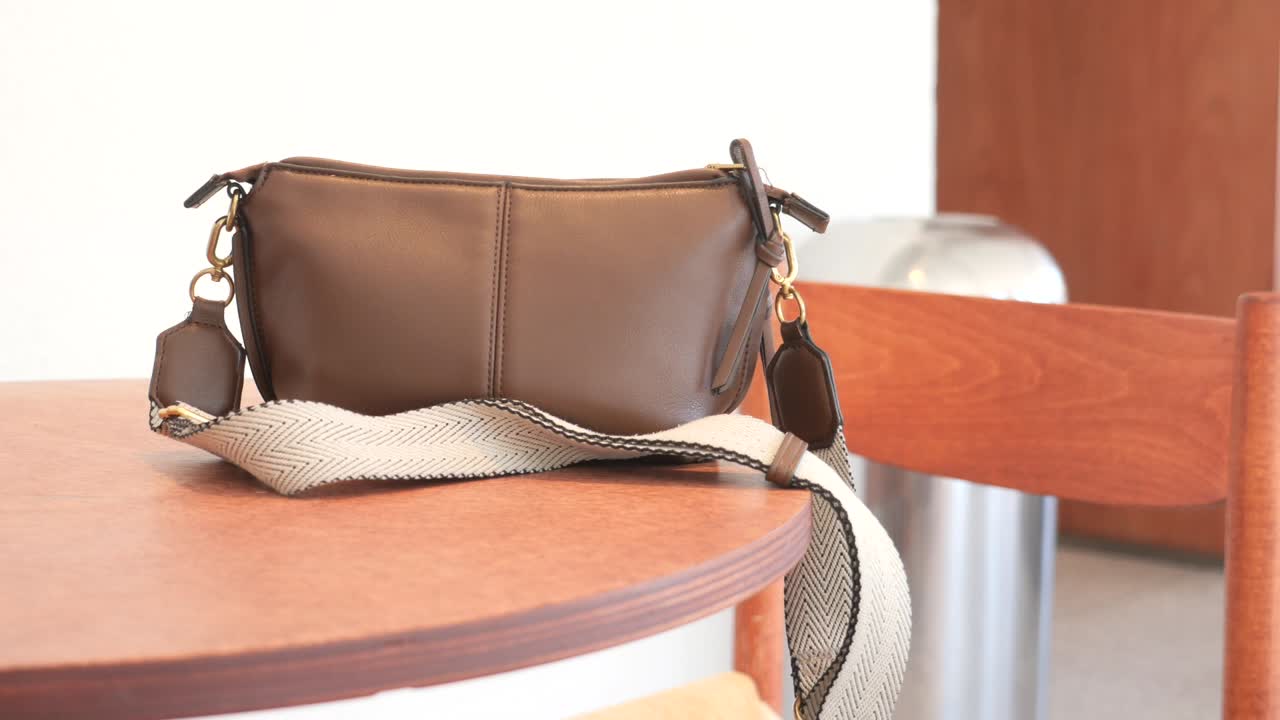 bolsa transversal de cuero marrón en la mesa