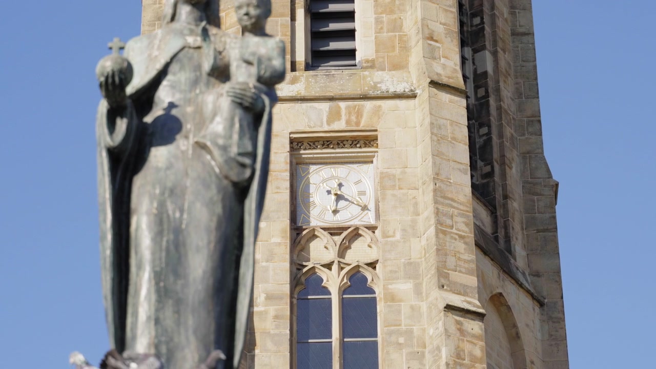 Nahaufnahme der Statue der Jungfrau Maria mit Kind und des Glockenturms der Ludwigskirche in Saarlouis, Deutschland