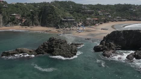 Aerial-orbits-rocks-at-Elephant-Beach-in-Mexican-coastal-town,-Mazunte
