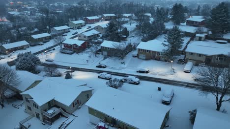 Dusk-descends-on-a-snowy-residential-street-with-houses-and-parked-cars