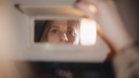 view of a hand with dark nail polish opening a car mirror. the scene shows the mirror being opened, focusing on the movement and the reflection. blurry, close-up shot, handheld camera