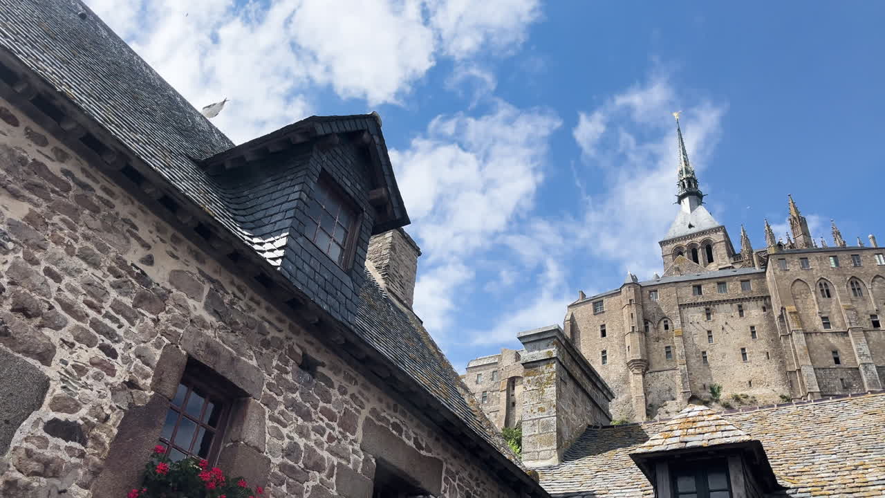 A beautiful view of Mont Saint-Michel towering above stone rooftops under blue skies