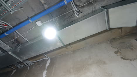 exposed pipes in industrial ceiling. industrial setting shows exposed metal structures, blue pipes, and ventilation ducts against a textured ceiling