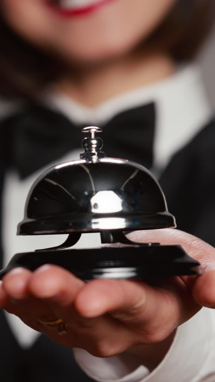Addetta alla reception che registra video verticali, mentre suona il campanello di servizio di fronte alla telecamera