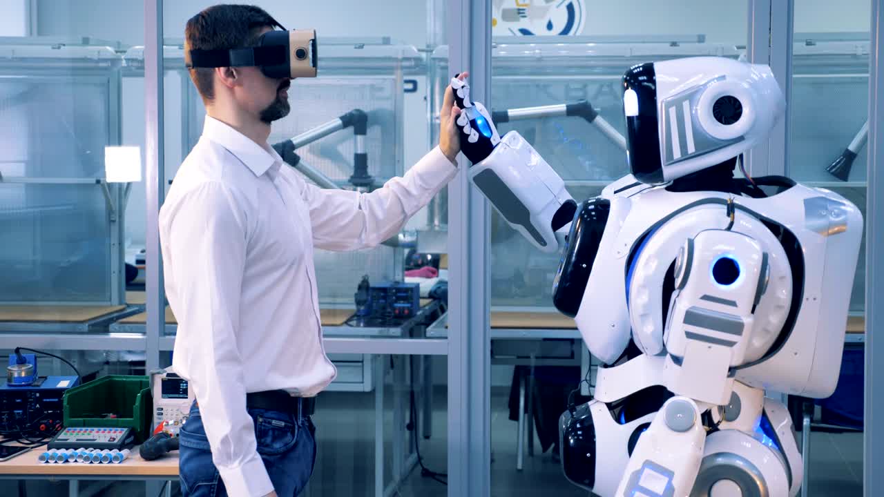 One man in VR glasses gives a robot high-five.