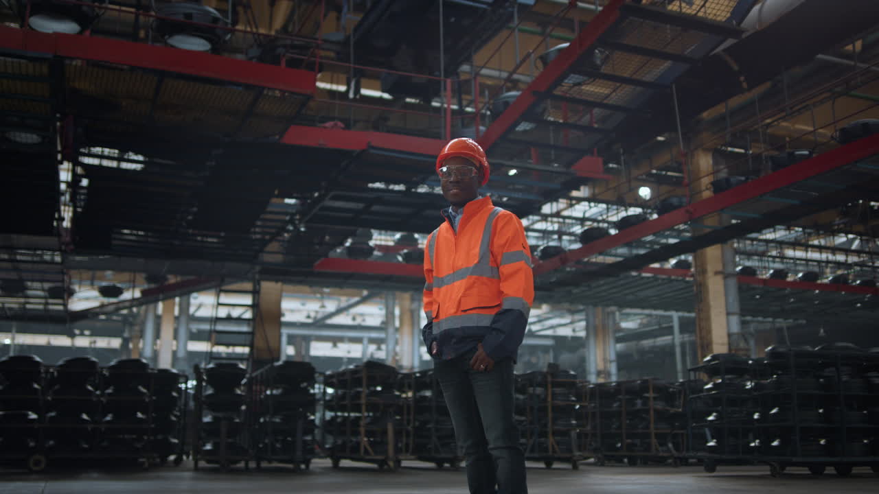 Industrial professional looking camera at huge modern manufacturing warehouse.