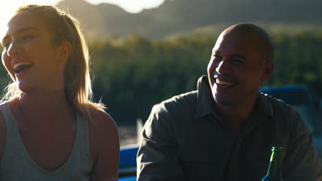 Group-Of-Friends-By-Pick-Up-Truck-On-Road-Trip-Drinking-Beer-By-Lake-At-Sunset