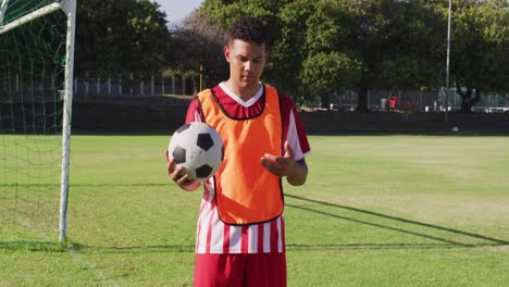 Video-of-diverse-male-biracial-football-player-standing-on-field-with-ball