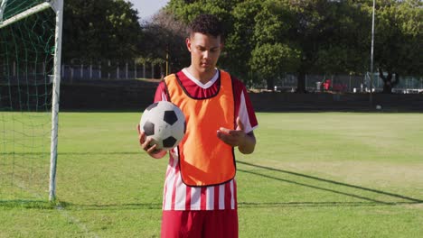 video of diverse male biracial football player standing on field with ball