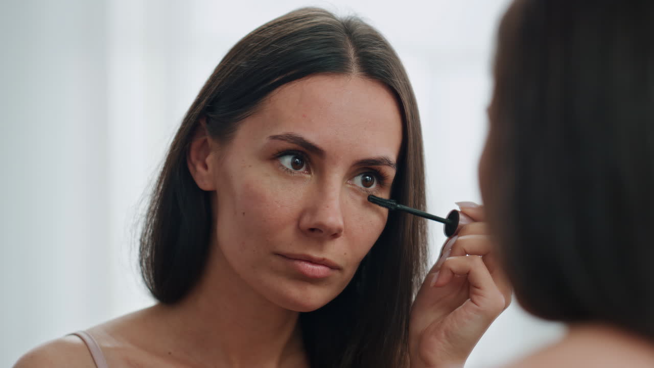 modelo satisfecho coloreando las pestañas lugar blanco de primer plano. dama aplicando máscara