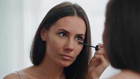 Satisfied-model-colouring-eyelashes-white-place-closeup.-Lady-applying-mascara