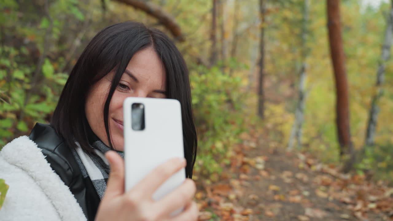 Mulher conversando alegremente ao ar livre, mulher usando jaqueta de couro enquanto desfruta de uma conversa amigável ao ar livre, mulher sorridente vestindo lenço e jaqueta participa de um bate-papo agradável ao ar livre em meio a árvores