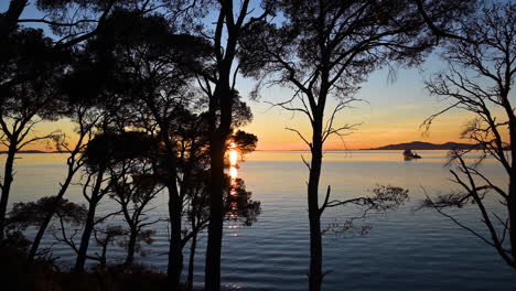 the beautiful bright fiery sunset sinking in the horizon over the mediterranean sea near saint-tropez, french riviera with a tug boat in the background - wide rolling