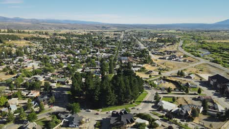 vuelo aéreo sobre las casas de la ciudad de trevelin y la plaza principal con montañas en el fondo, patagonia argentina