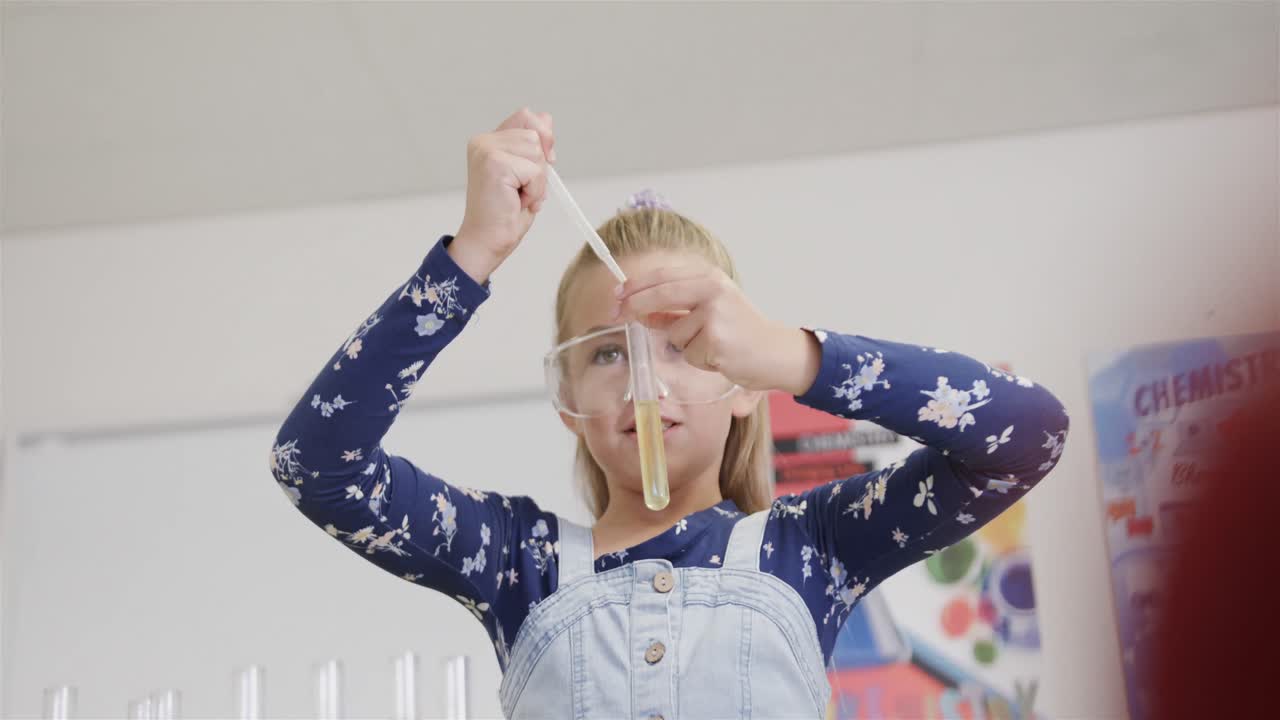 Focused caucasian schoolgirl doing experiment in elementary school chemistry class, slow motion