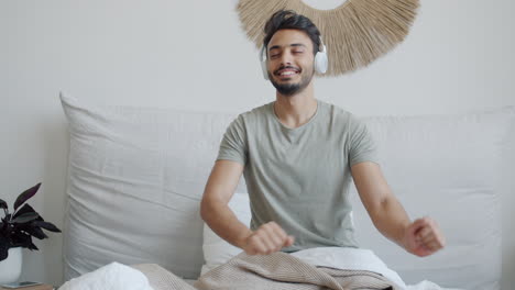 man dancing to music in bed